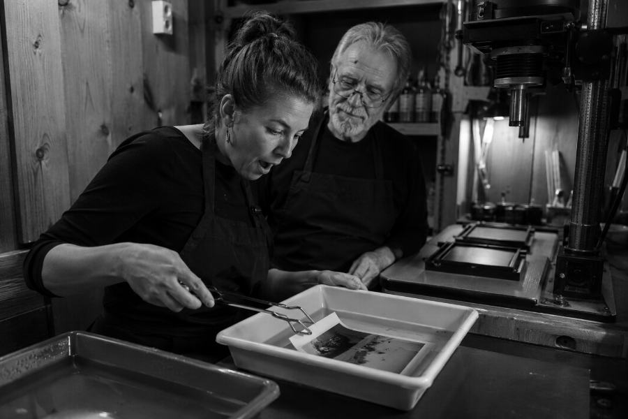 Una fotografía apareciendo sobre el papel dentro de la bandeja del cuarto oscuro, junto a la ampliadora
