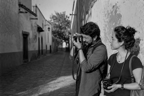 Una pareja fotografiando una calle empedrada de Tequisquiapan, cada persona con su propia cámara de 35 mm